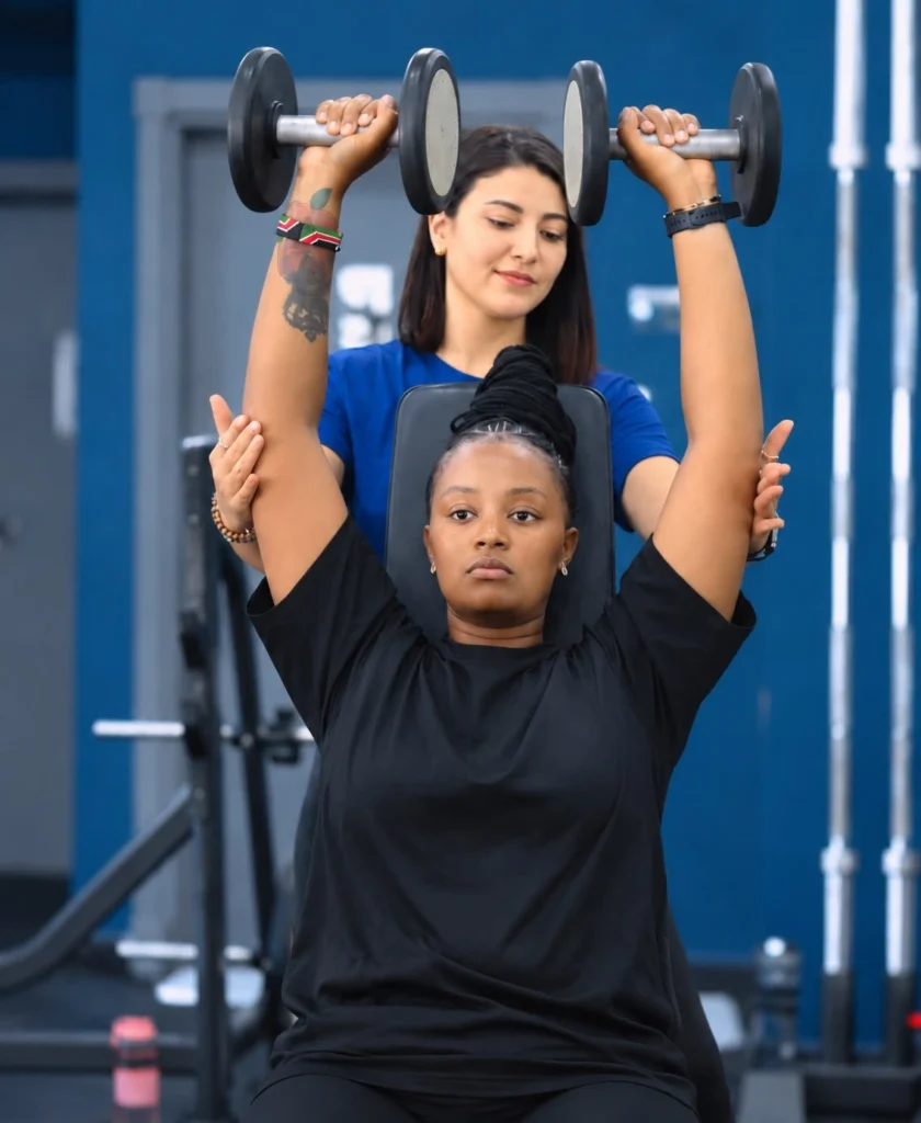 Personal trainer guiding a client through an overhead dumbbell press